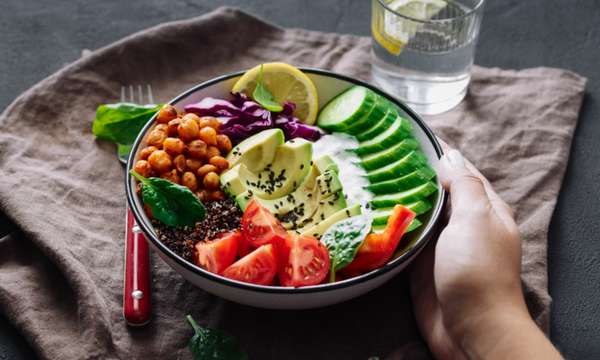 Ensalada fresca con vegetales y alimentos naturales sobre mesa blanca